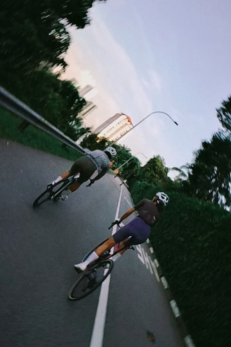 Two cyclists leaning into a turn on a city road