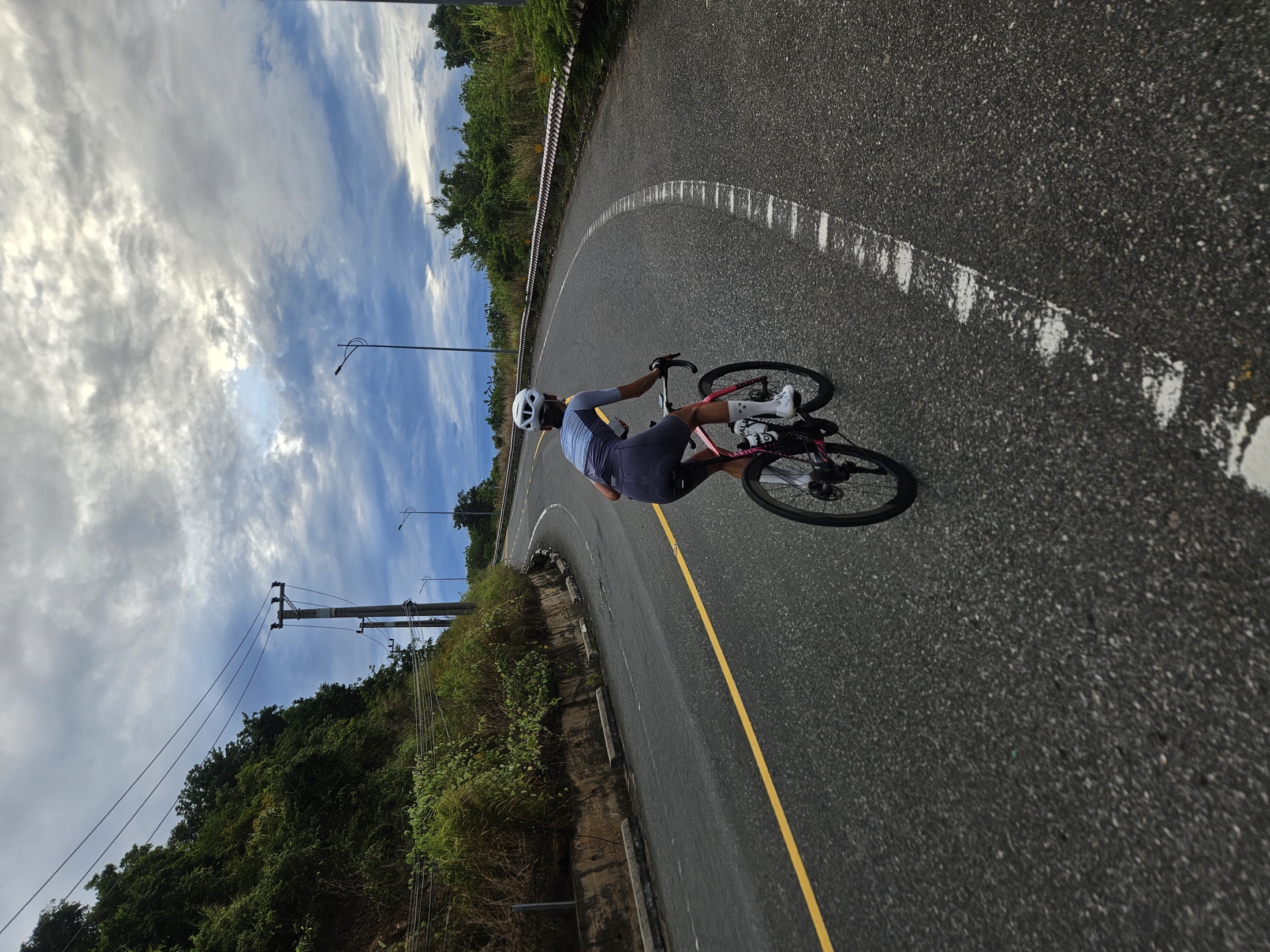 A cyclist climbing a winding mountain road beneath a wide sky