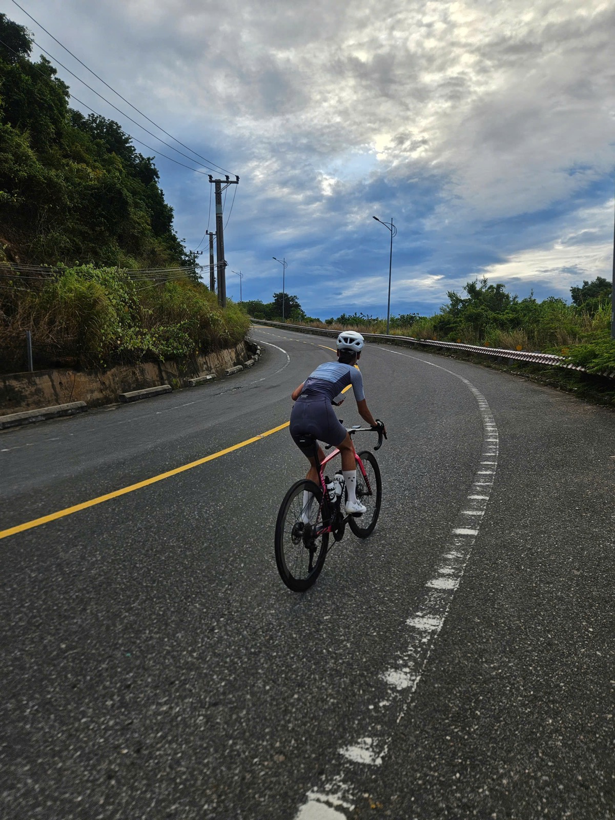 A cyclist riding up a wide mountain road