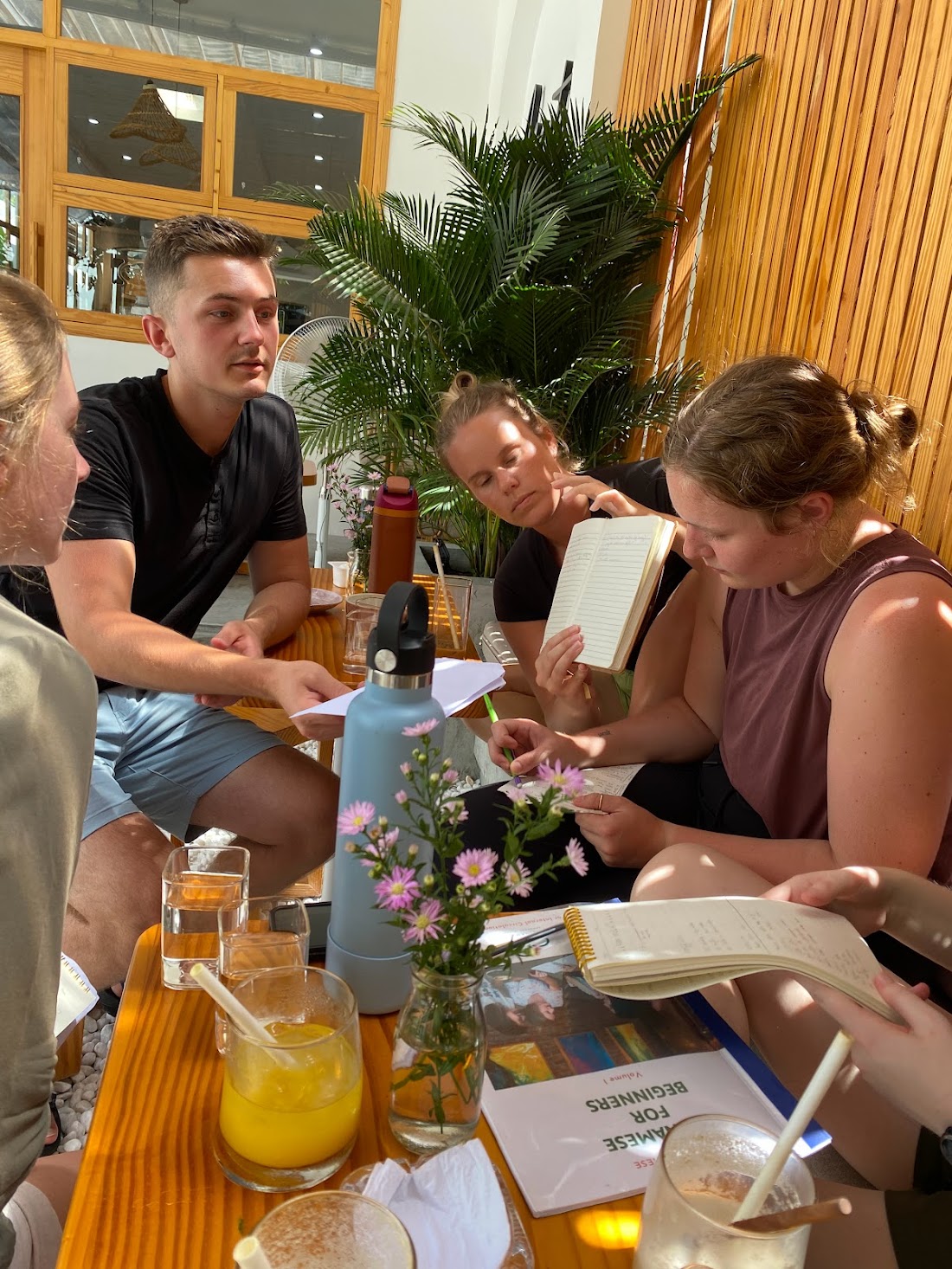 Diem guiding a Vietnamese learning session with a small group at a café